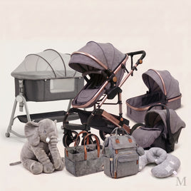 A coordinated baby travel and care set arranged on a light neutral studio background, including a bassinet, stroller, car seat, infant car seat, diaper bag, tote bag, neck pillow, and a plush elephant toy. The products are predominantly gray with black interiors and rose-gold metallic trim.